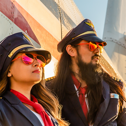 Two disheveled pilots wearing red aviator sunglasses with red lenses lean against an airplane, looking into the sunset.