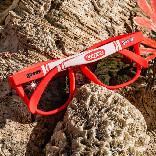 Back view of folded coral sunglasses w/ white Crayola marker pattern+burnt orange reflective lenses on a reef.