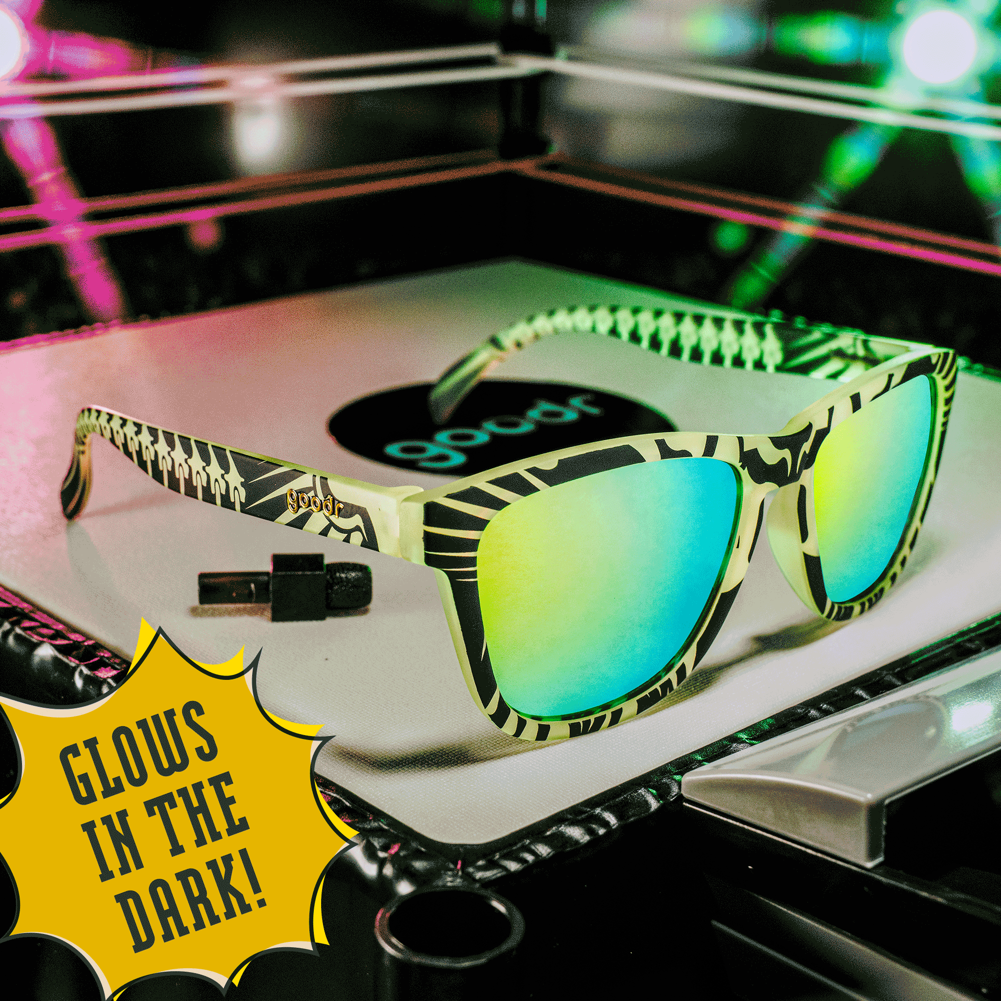 Three-quarter view of green and black glow-in-the-dark shades with green reflective lenses, posed in a mini wrestling ring.