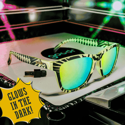 Three-quarter view of green and black glow-in-the-dark shades with green reflective lenses, posed in a mini wrestling ring.