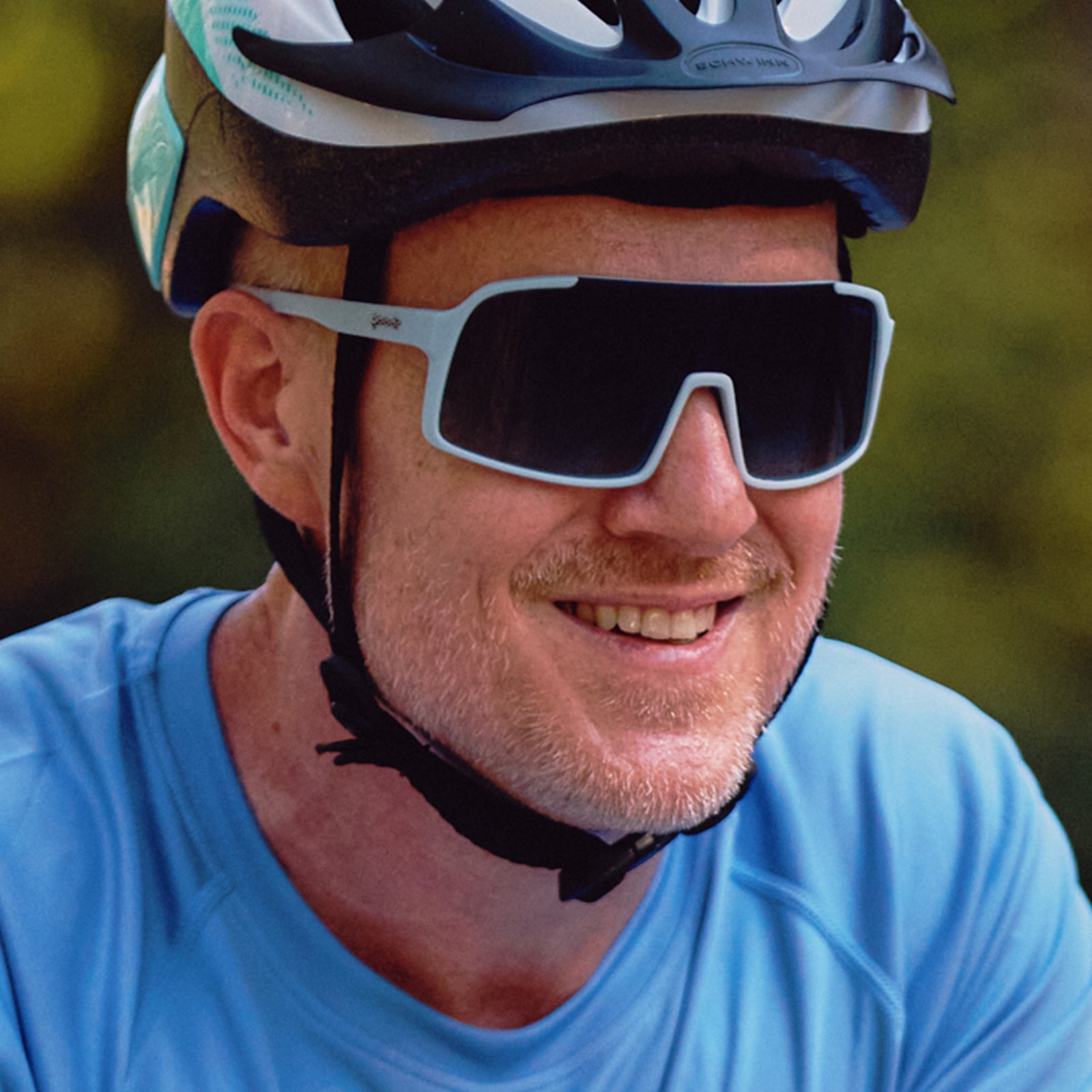 A cyclist wearing ASTRO G sunglasses and a blue jersey and helmet.