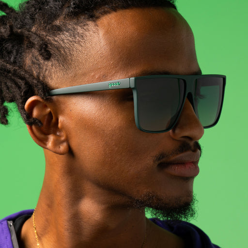 Closeup profile shot of a stylish man rocking dark green oversized flat-top sunglasses with green gradient lenses.