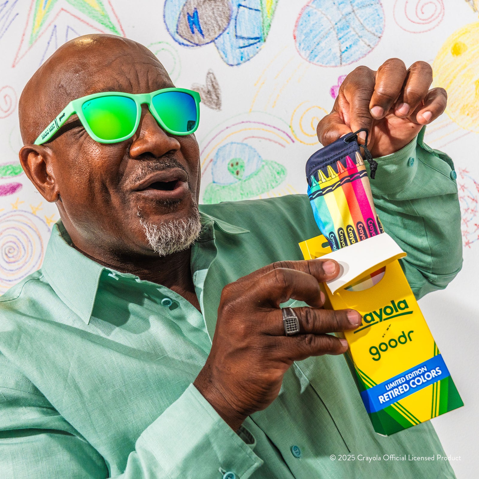A delighted older man wearing Crayola Magic Mint shades opens the Crayola box-themed packaging