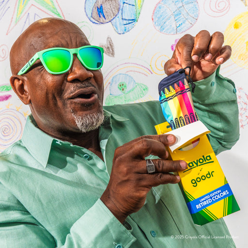 A delighted older man wearing Crayola Magic Mint shades opens the Crayola box-themed packaging
