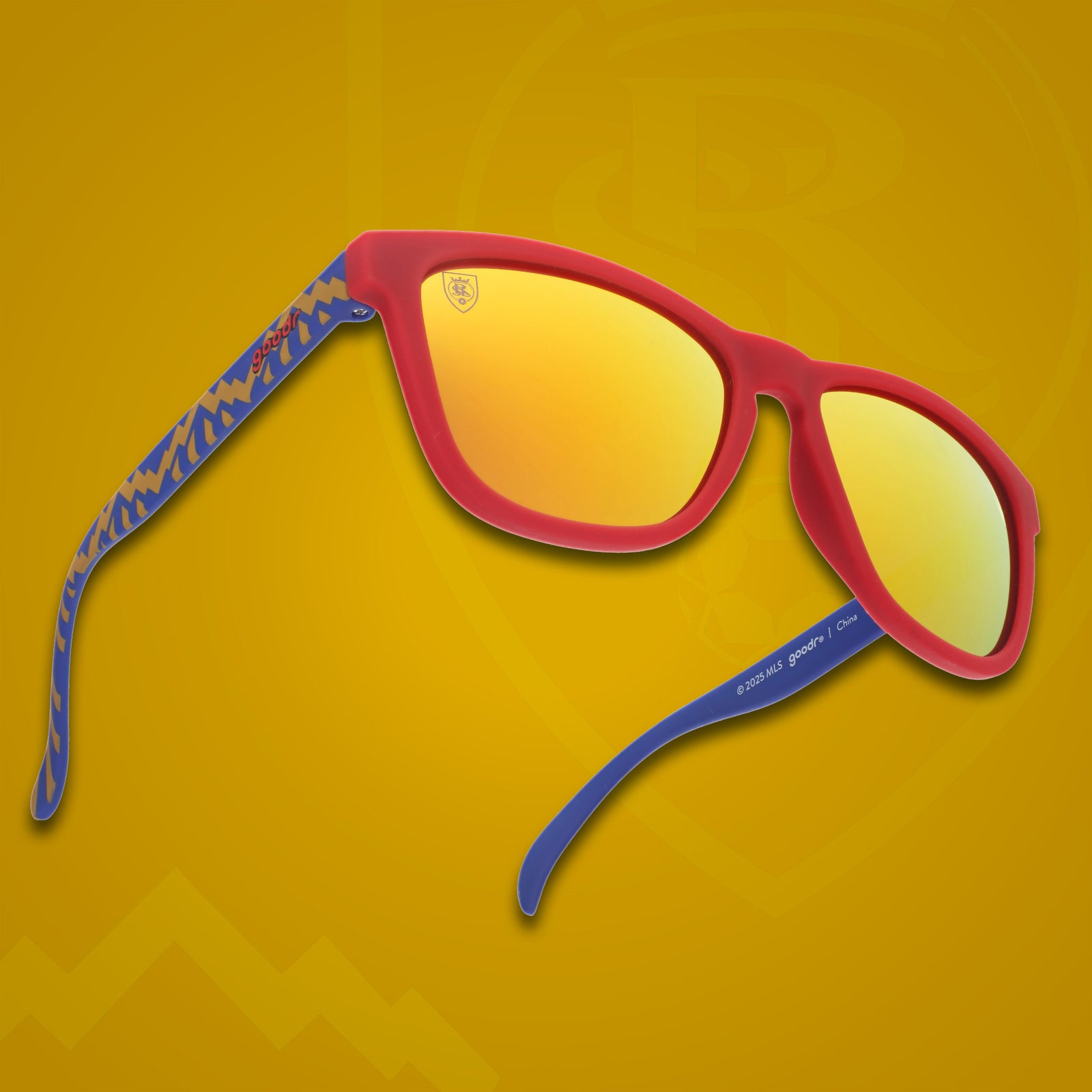 Three-quarter angle view of MLS Real Salt Lake shades. Red+blue patterned frames. Amber reflective lenses.