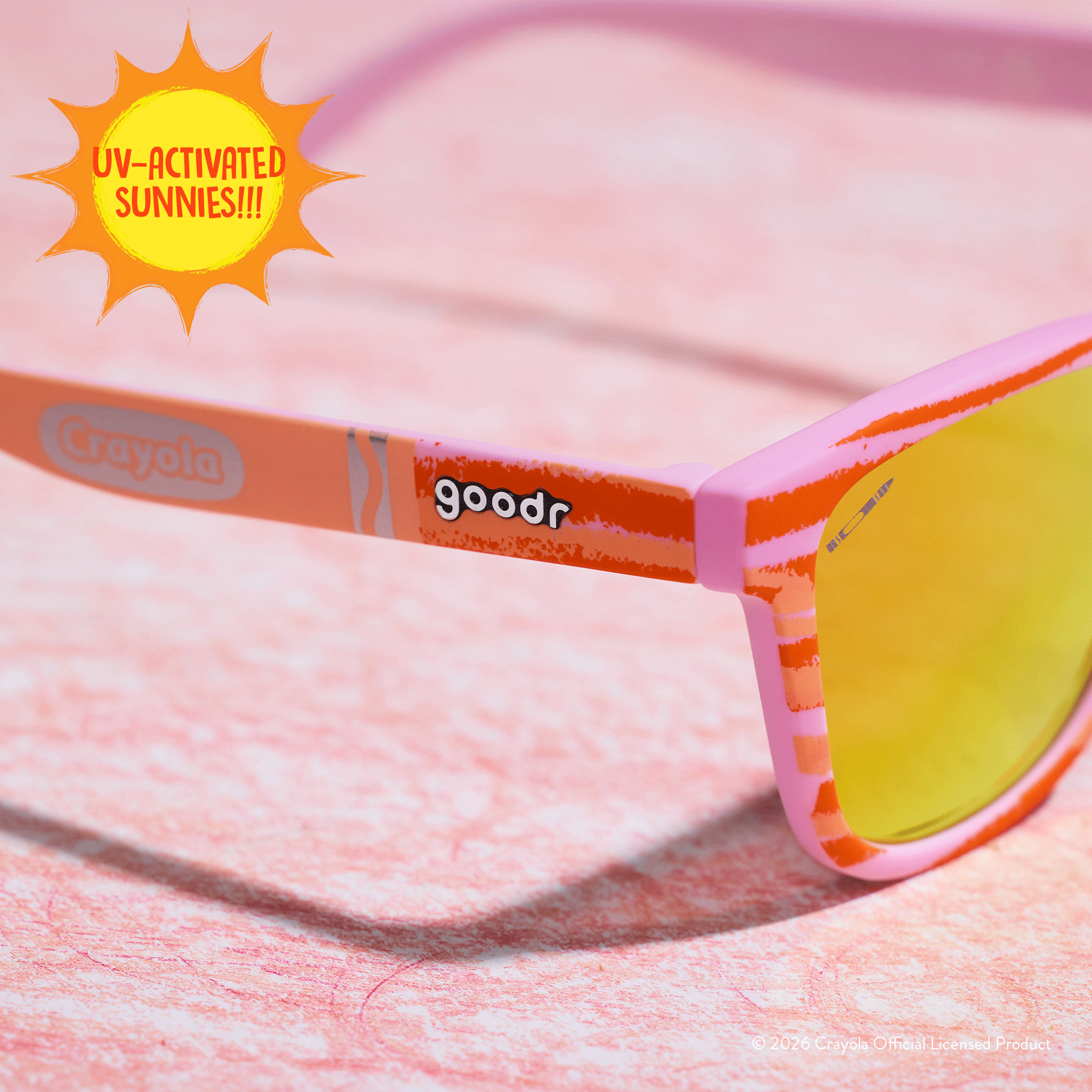 Close-up of Crayola goodr UV-activated Party Fish sunglasses with bone-to-magenta frames and amber reflective lenses.