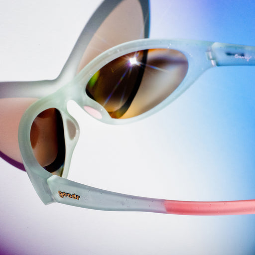 Back view of light blue sparkly goodr sunglasses with pink temple grips on a blue and purple ombre background