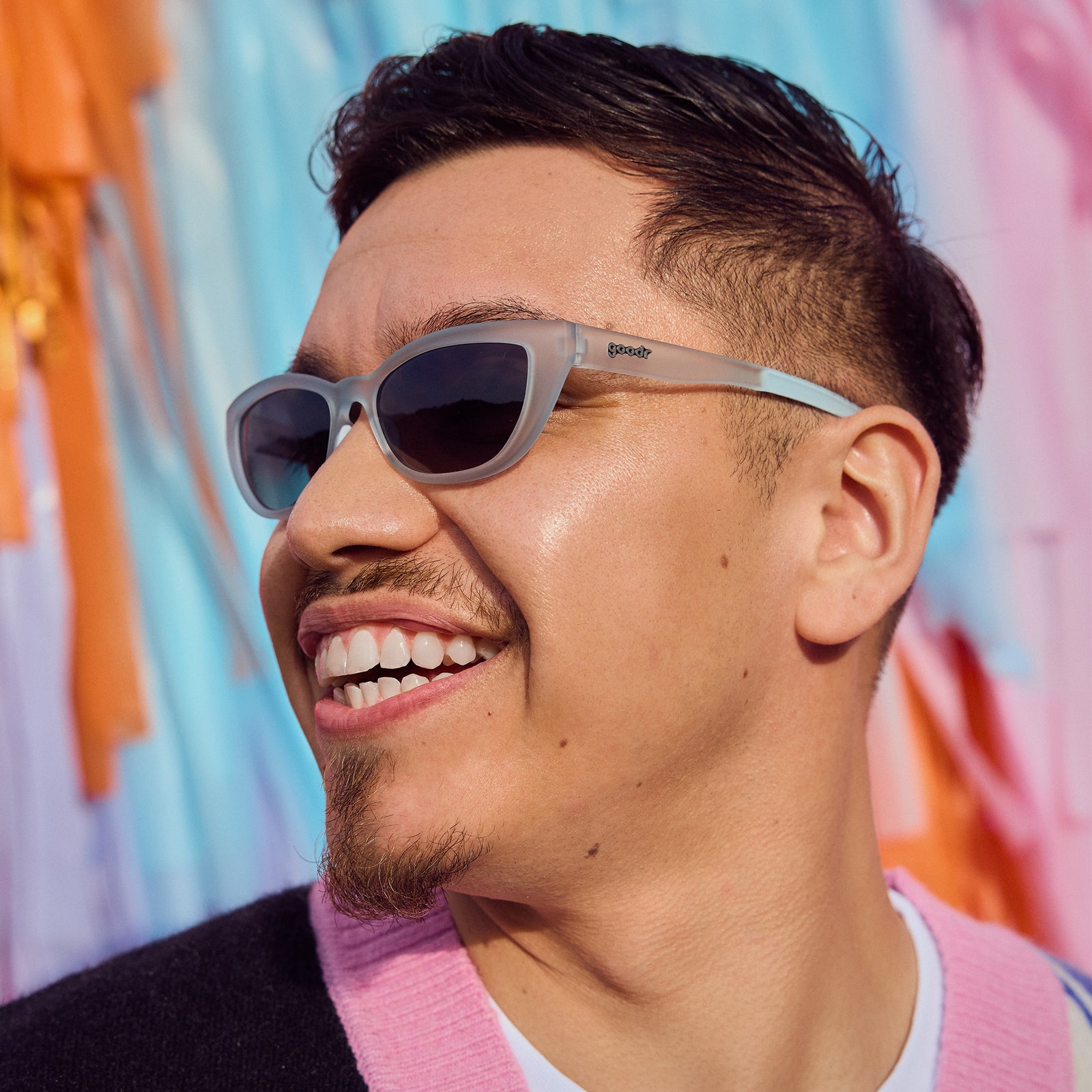 Left profile of a man wearing light blue cat-eye sunglasses with gradient violet lenses.