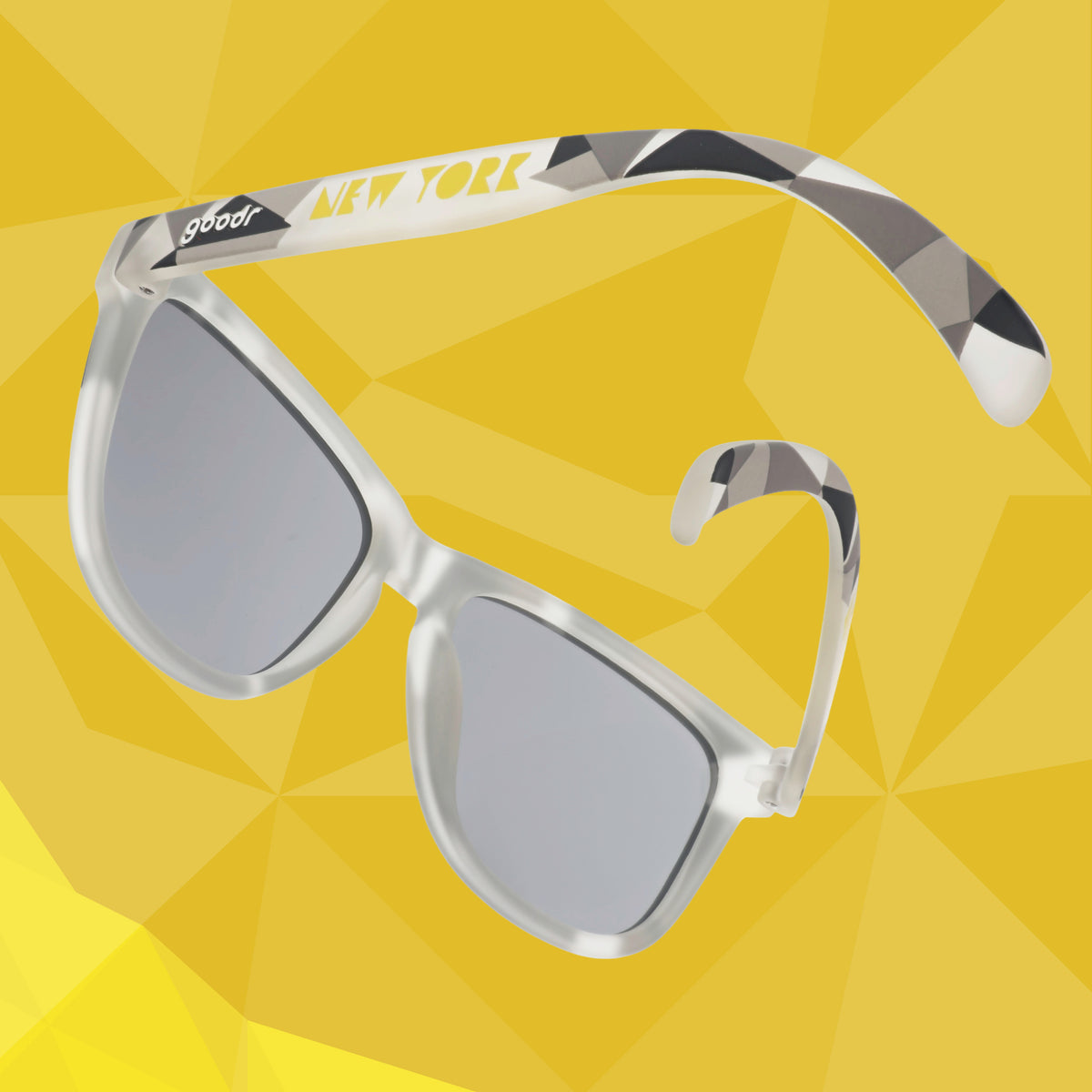 Left temple view of gray sunglasses with a tonal geometric pattern and chrome reflective lenses against a yellow geometric-patterned background.