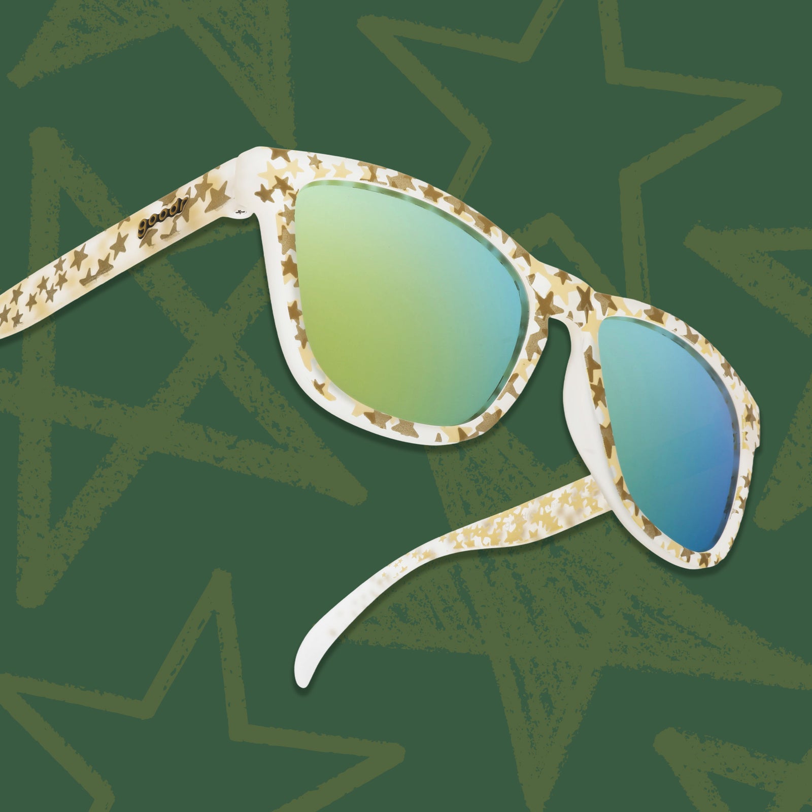 Three-quarter angle view of clear OGs with a gold star design and gold reflective lenses on a green backdrop with stars.