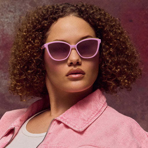 Woman wearing pink sunglasses and a pink jacket against a red background