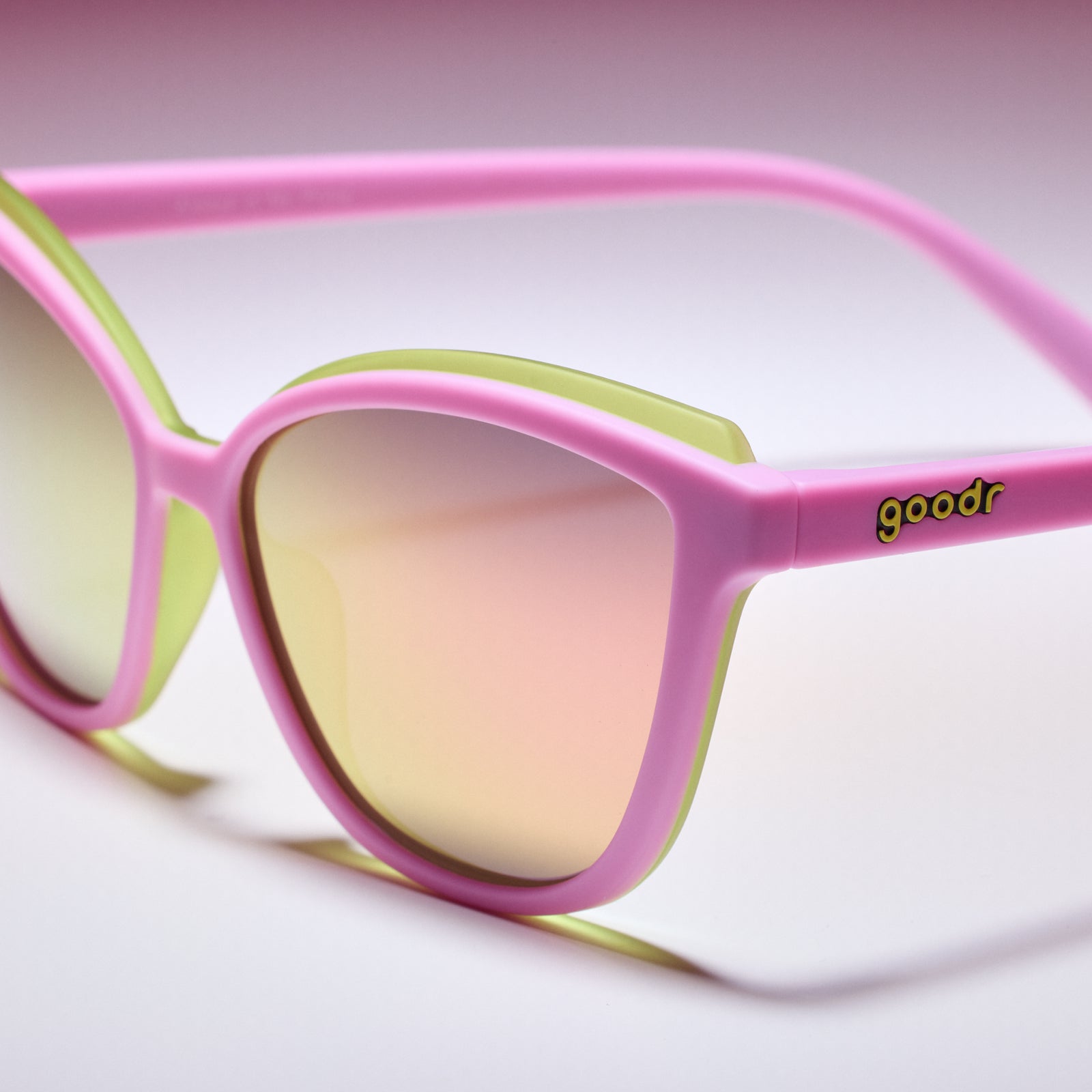 Pink and green sunglasses with 'goodr' logo on a white background