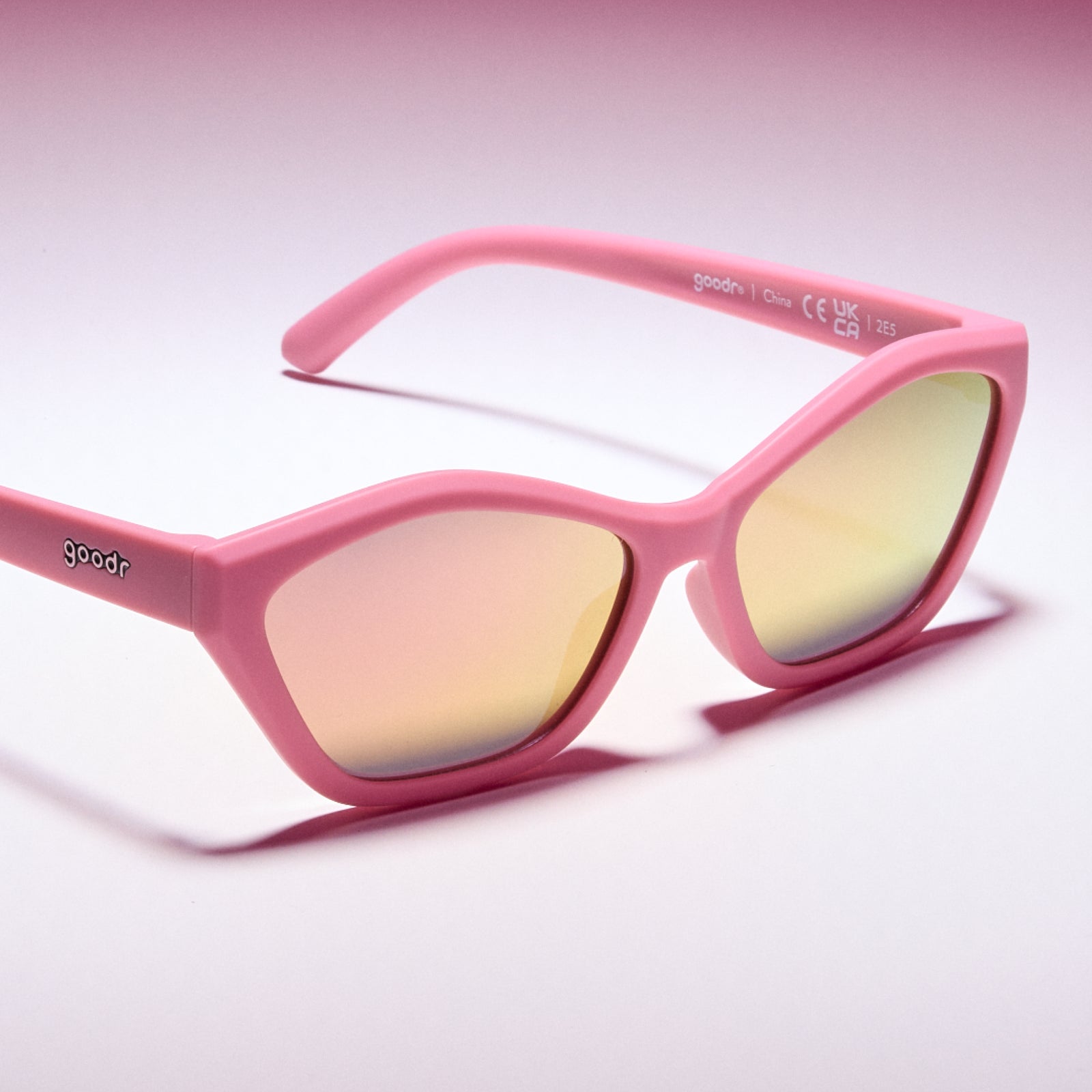 Pink sunglasses with reflective lenses on a light pink background