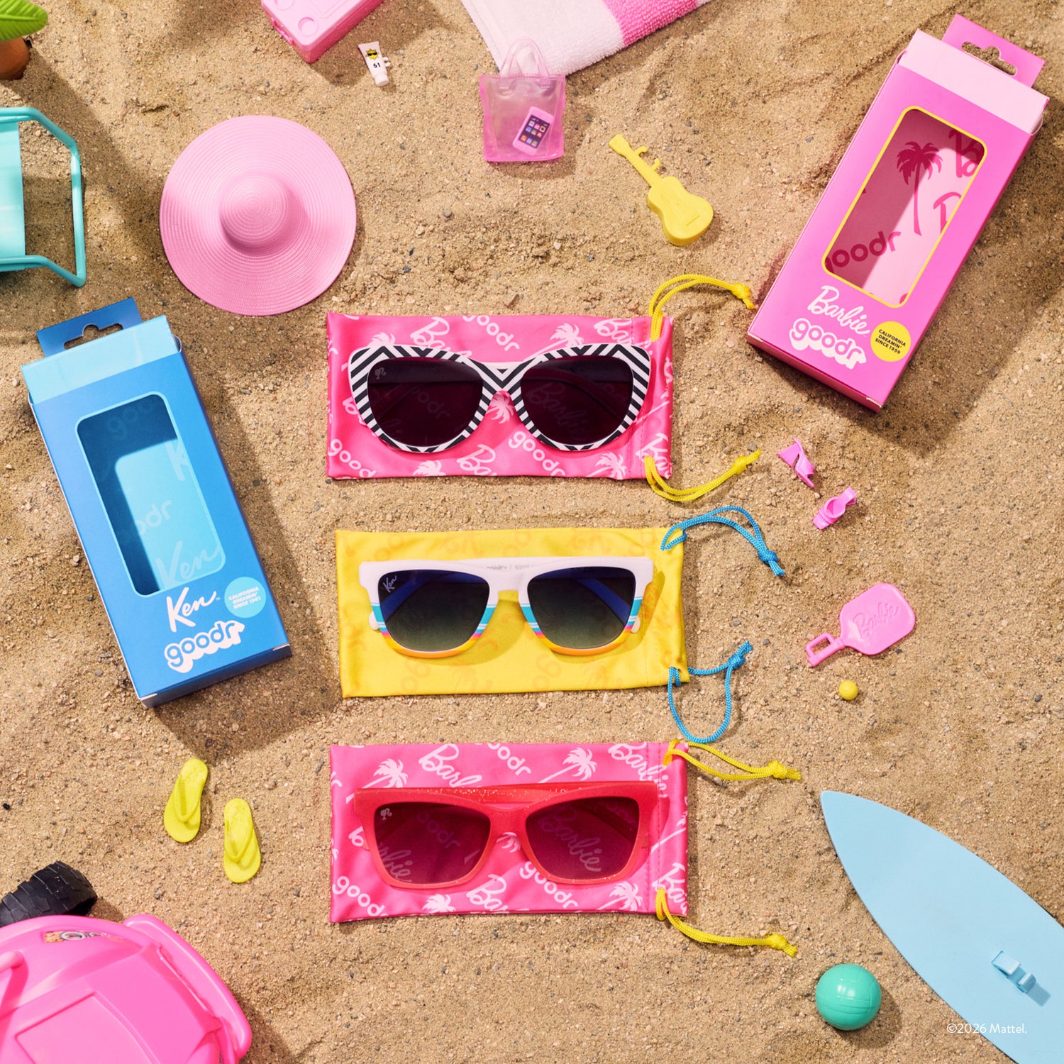 Sunglasses with colorful cases and beach accessories on sand