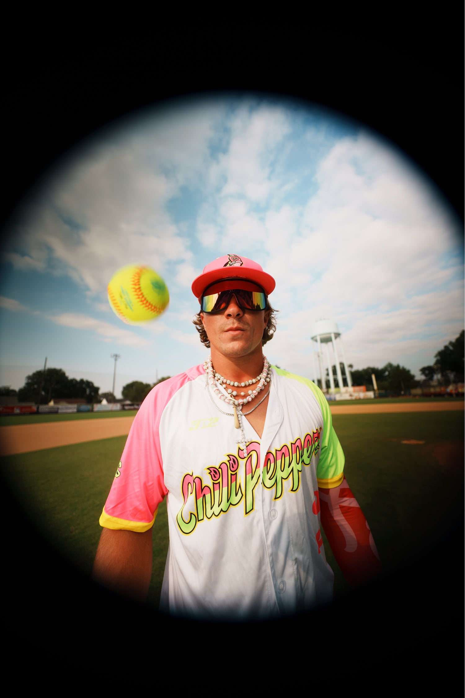 Person holding a tennis ball on a sports field with a colorful jersey and accessories.