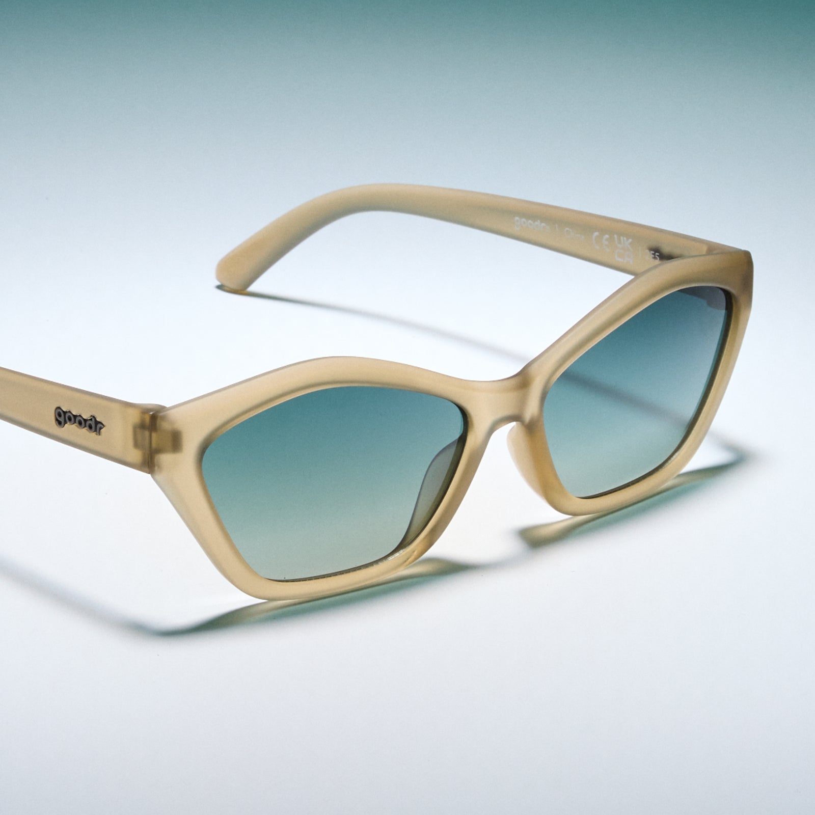 Beige sunglasses with gradient lenses on a light blue background