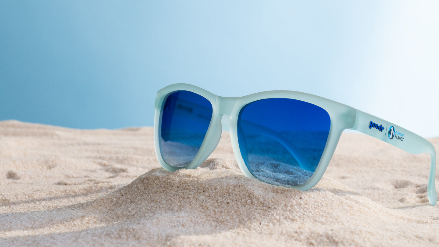 Recycled blue sunglasses sitting on the beach.
