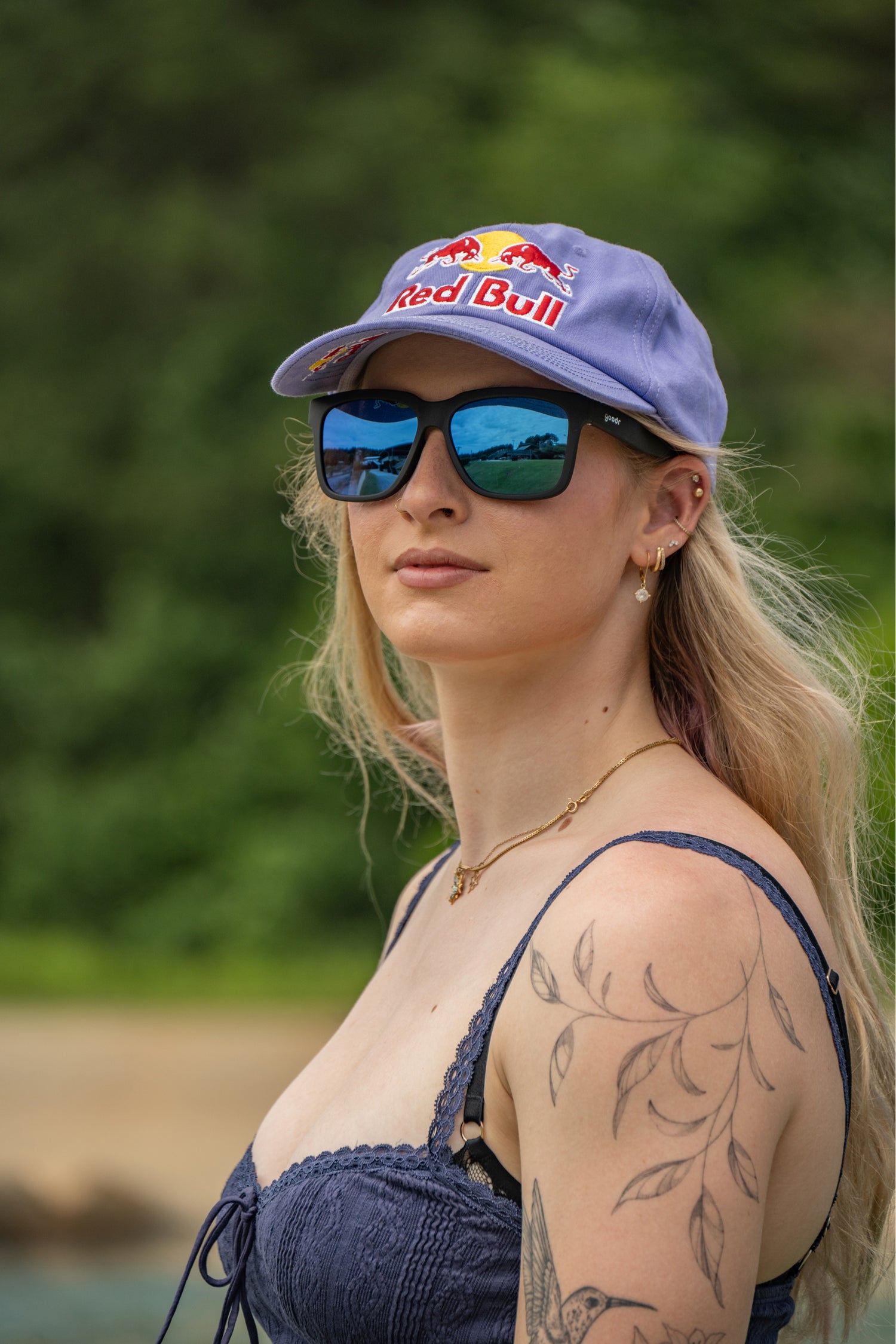 Woman wearing a Red Bull cap and sunglasses with a blurred natural background