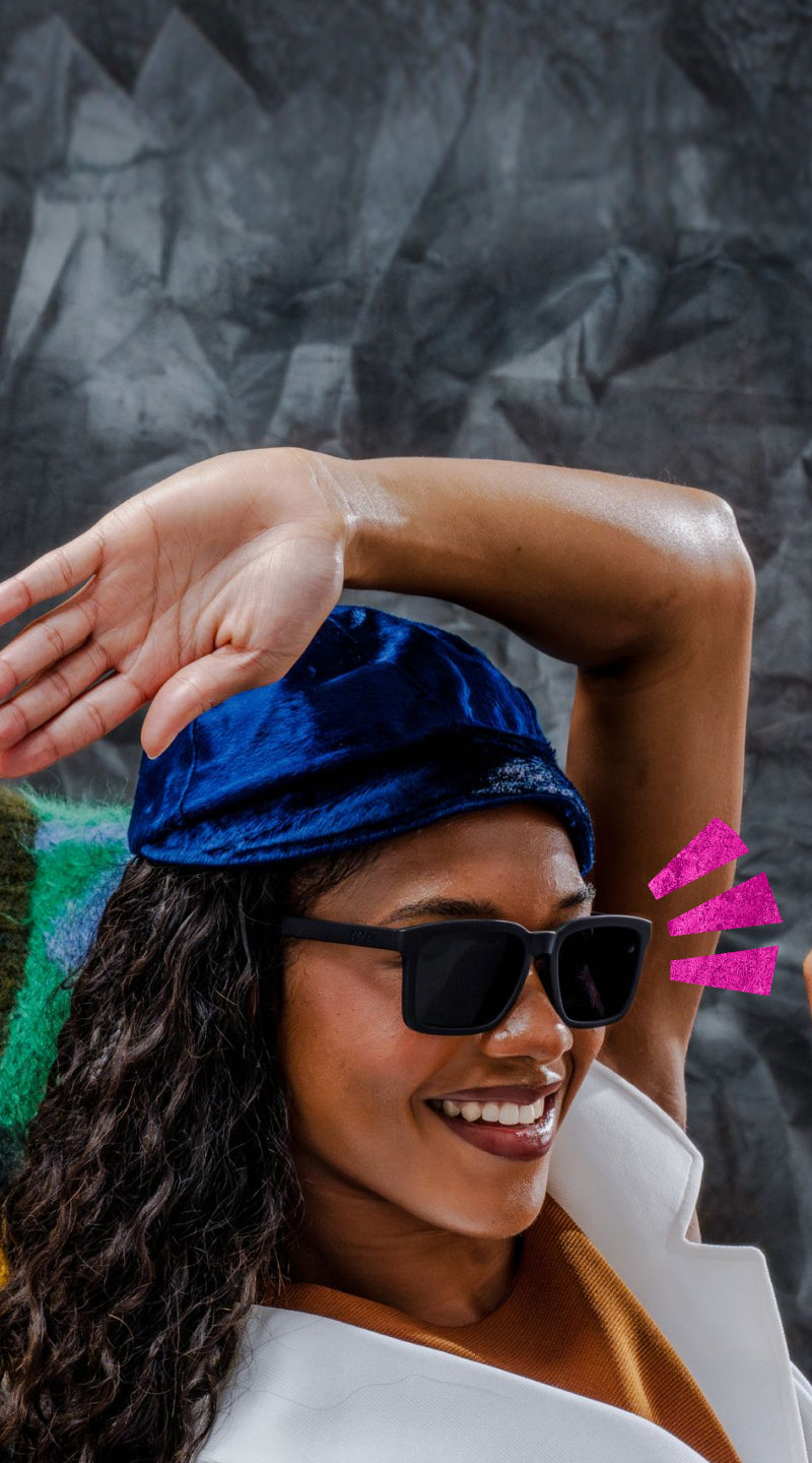 Woman wearing a blue cap and sunglasses with a dark textured background