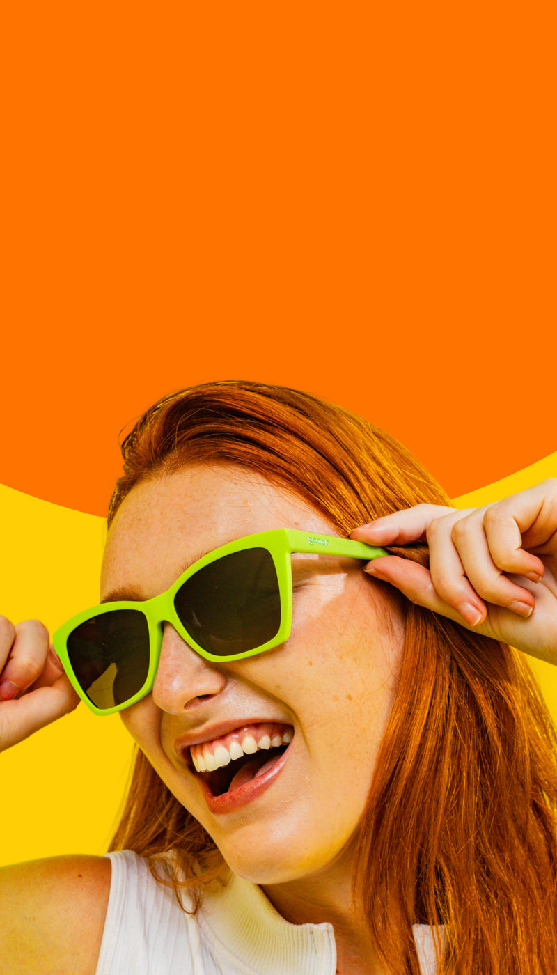 Person wearing bright green sunglasses with a colorful background