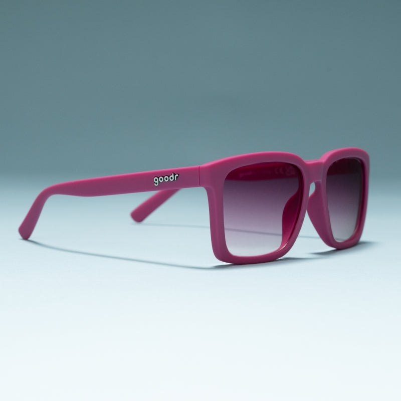 Three-quarter angle view of purple shades w/ purple gradient lenses+ a classic square silhouette on a flat surface.