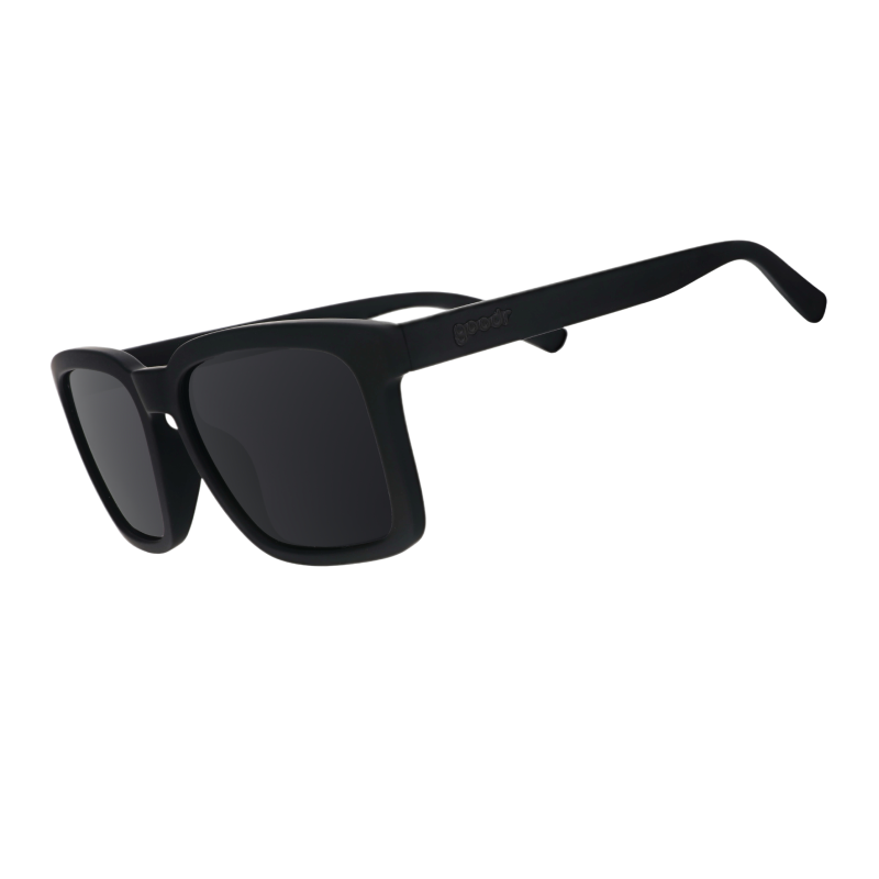 Three-quarter angle view of black sunglasses w/ a square silhouette & black nonreflective lenses tilted down.