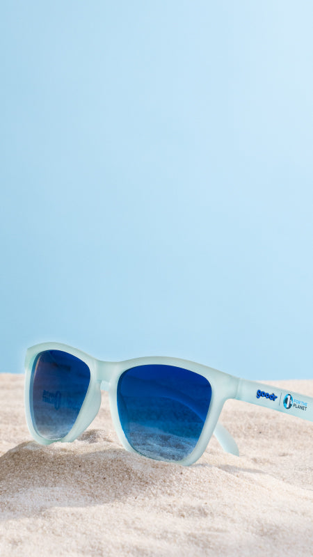 Recycled blue sunglasses sitting on the beach.