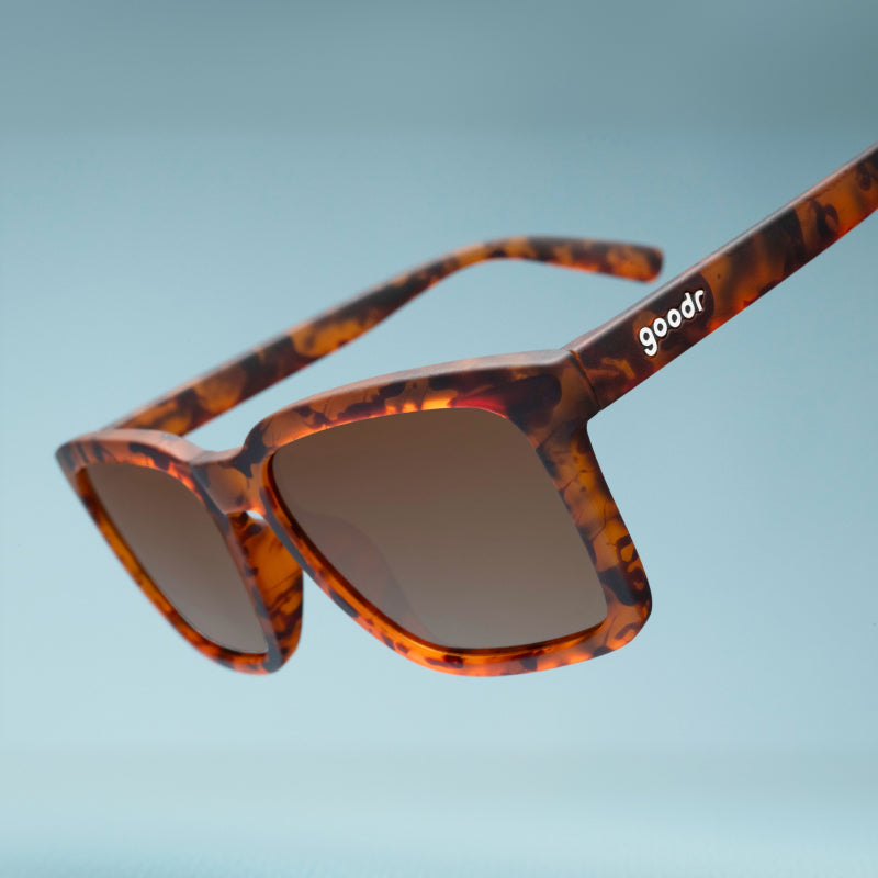 Angled close-up view of translucent brown square sunglasses w/ a tortoiseshell pattern & brown nonreflective lenses.