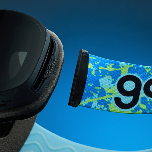 Close-up of blue and lime splatter goodr goggle strap attached to black ski goggles.