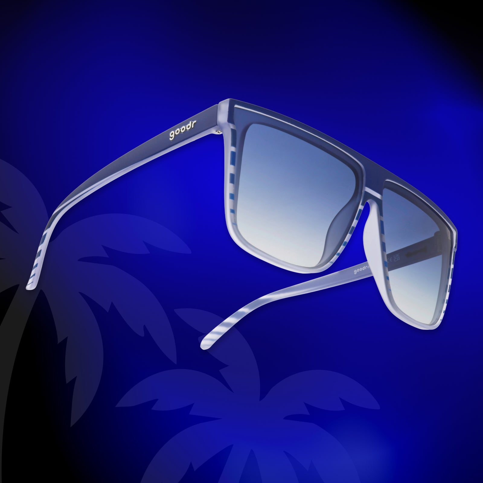 Translucent blue-purple, retrowave-striped flat-top Fly G sunnies against a stylized, vivid blue background with palm trees.