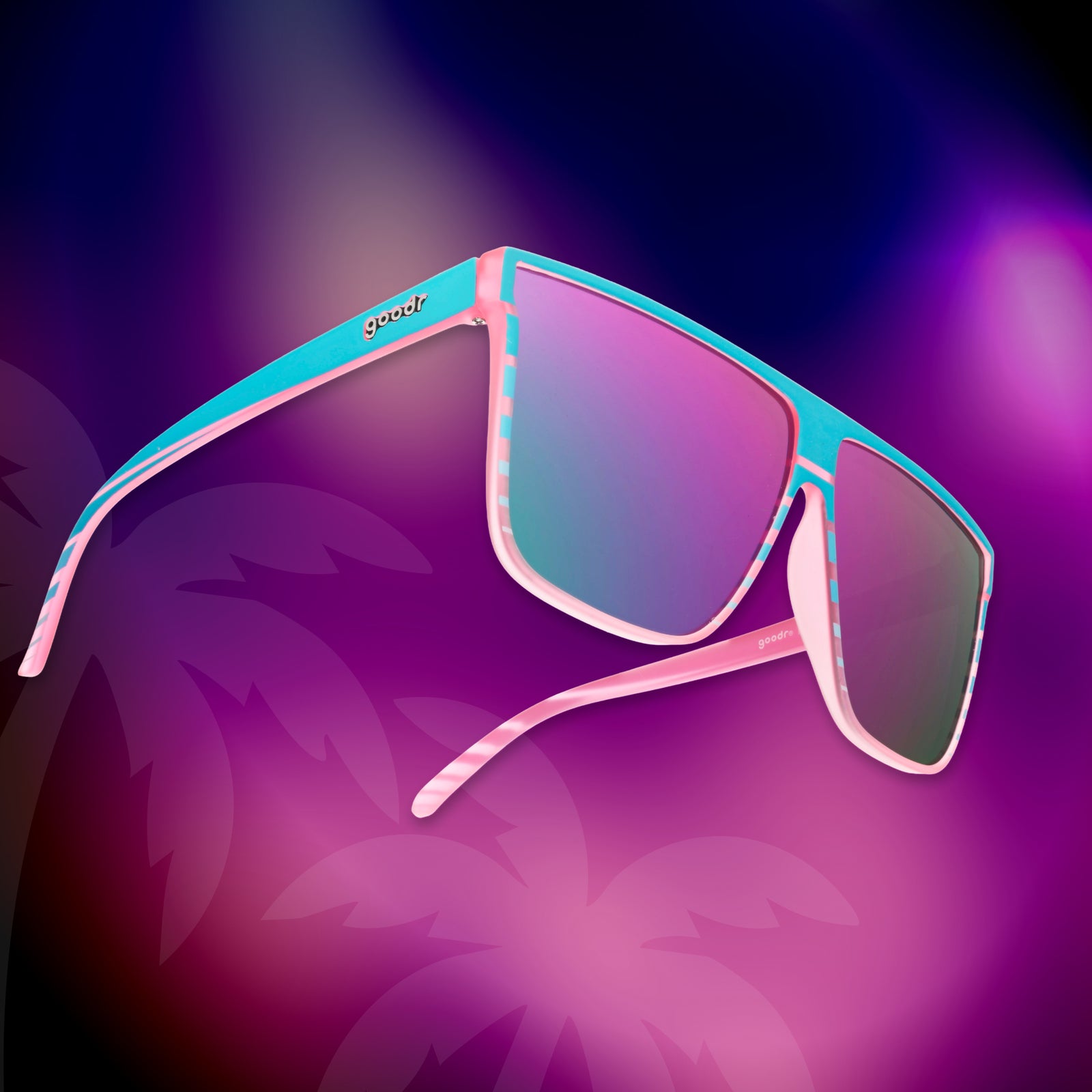 Translucent pink flat-top Fly G sunglasses with a teal retrowave design float on a tropical hot pink-purple background.