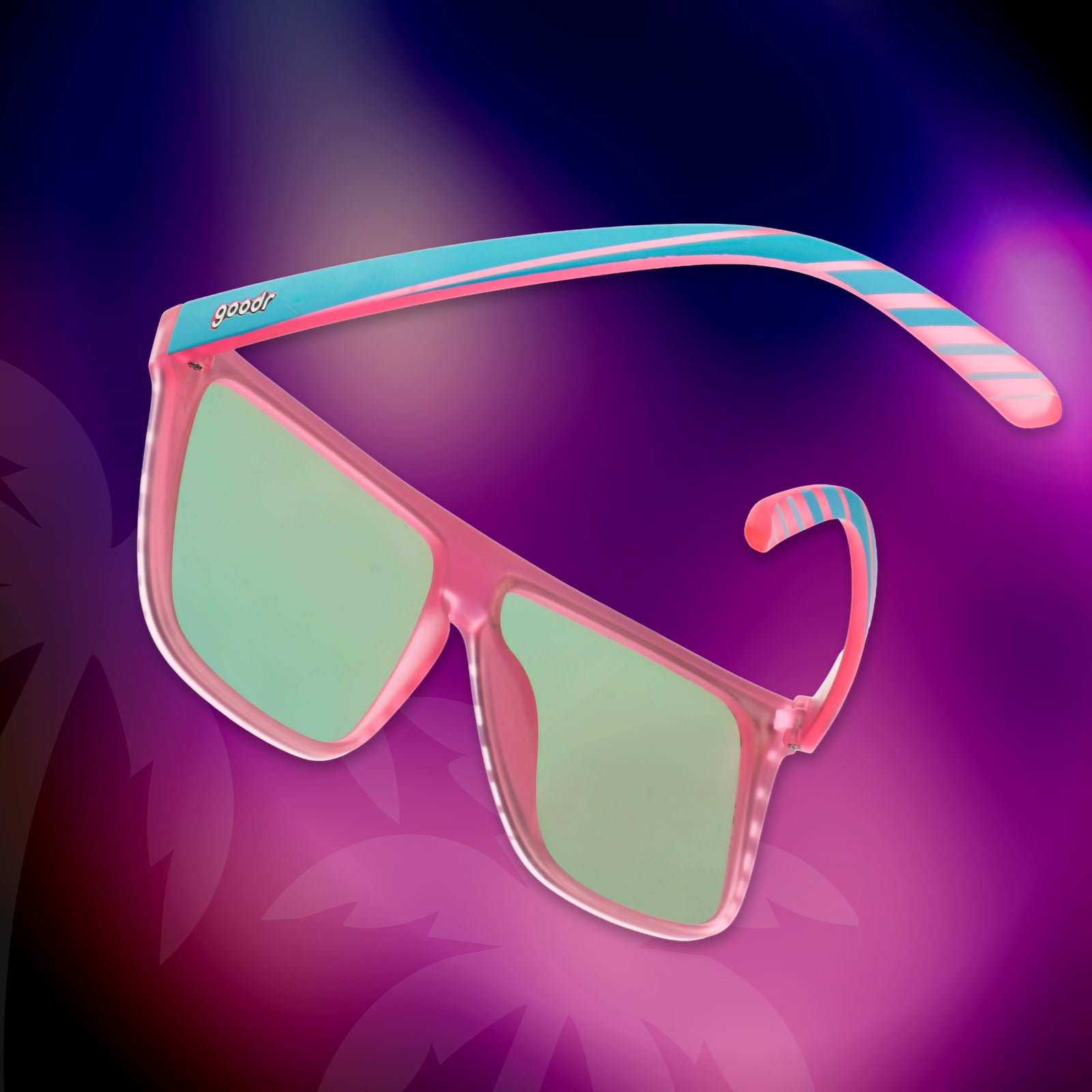A pair of retro flat-top Fly Gs photographed from behind, floating against a vivid hot-pink-and-purple palm tree background.