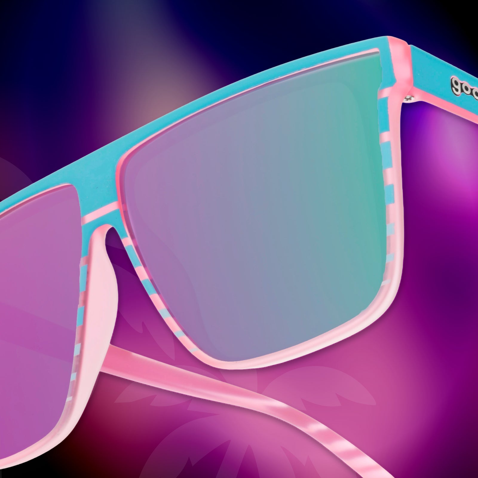 Close-up of the temple of a pair of retro-striped, pink-teal Fly G sunglasses against a tropical hot pink-purple background.