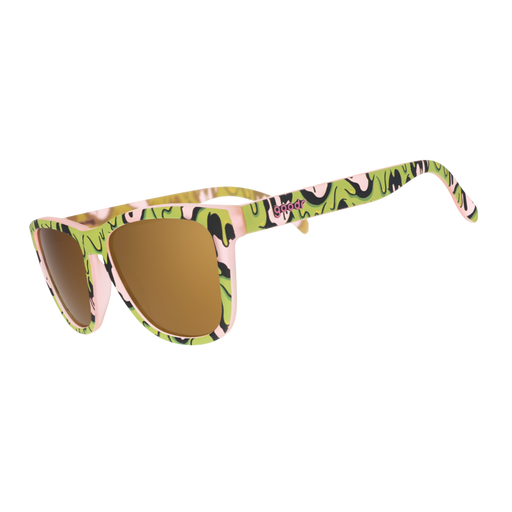 Pink sunglasses with gold lenses and a gooey green-and-black slime pattern, shown at an angle on white.