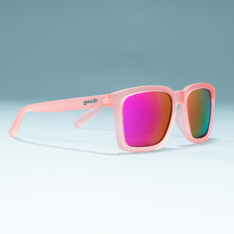Three-quarter angle view of translucent light pink square shades w/ pink reflective lenses on a flat surface.