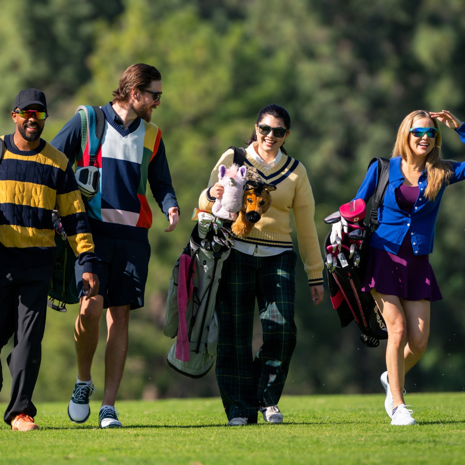 Four people walking on a golf course with golf bags.